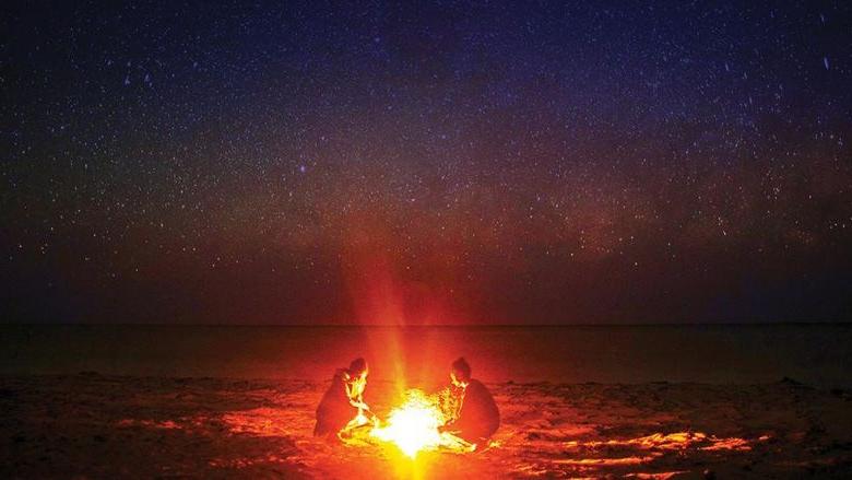 两个人围坐在篝火旁，星空斑驳