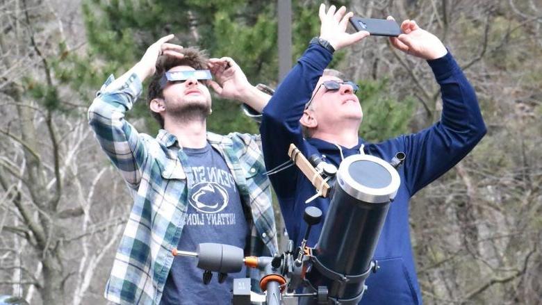 两个人用望远镜仰望日食